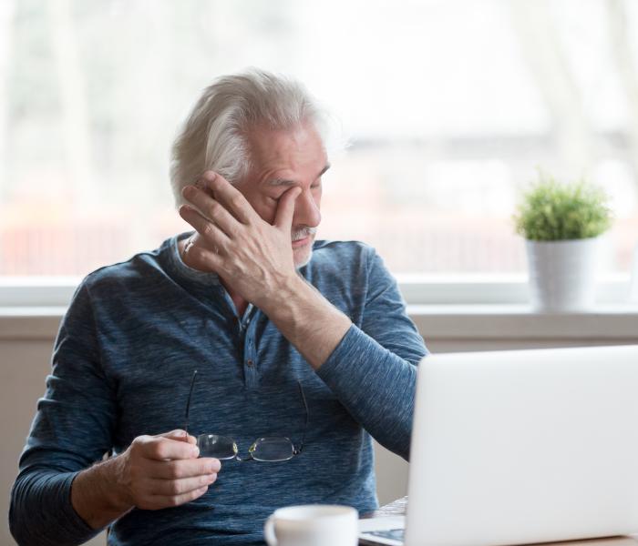 Medewerker zit vermoeid achter de laptop