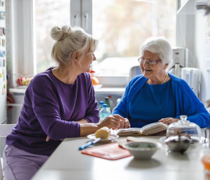 Mantelzorger en senior zitten aan tafel