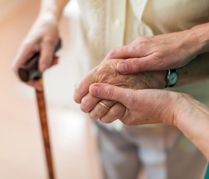 Thuishulp houdt handen van senior vast