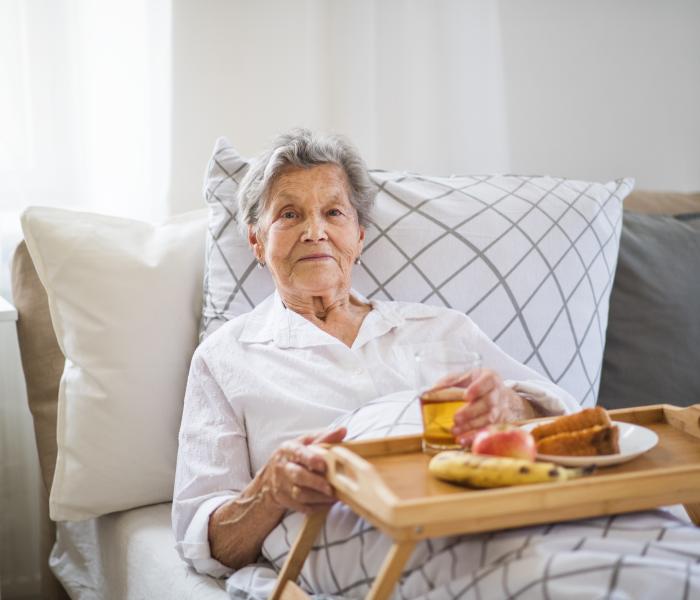 Senior op de bank met een maaltijd