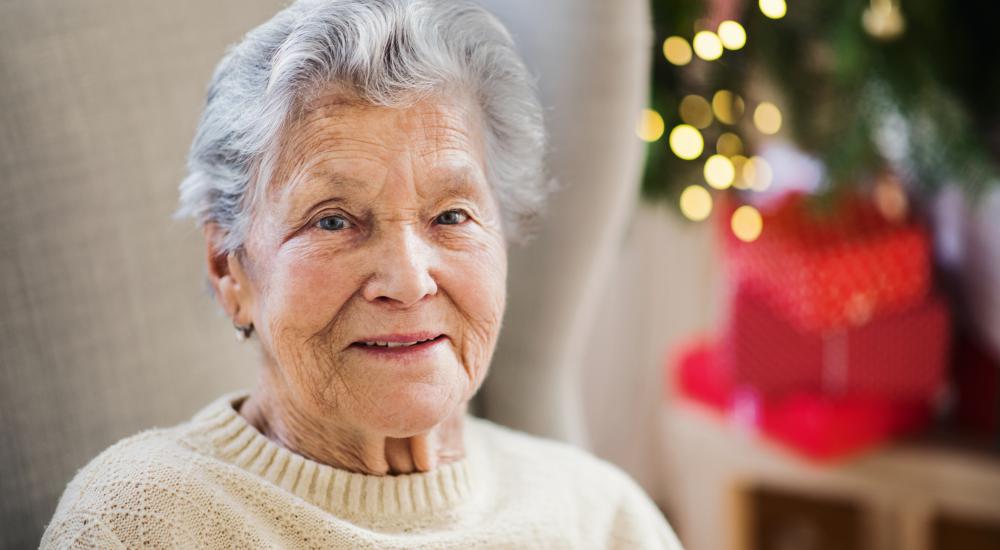 Senior alleen thuis met kerstboom