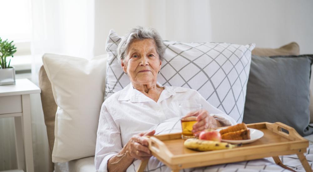 Senior op de bank met een maaltijd