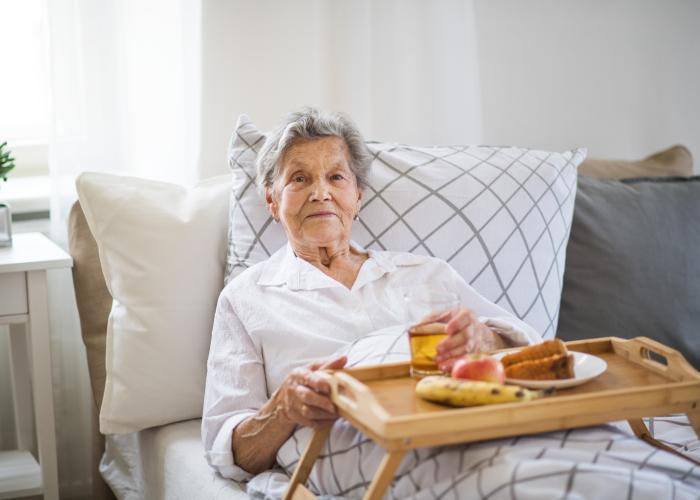 Senior op de bank met een maaltijd