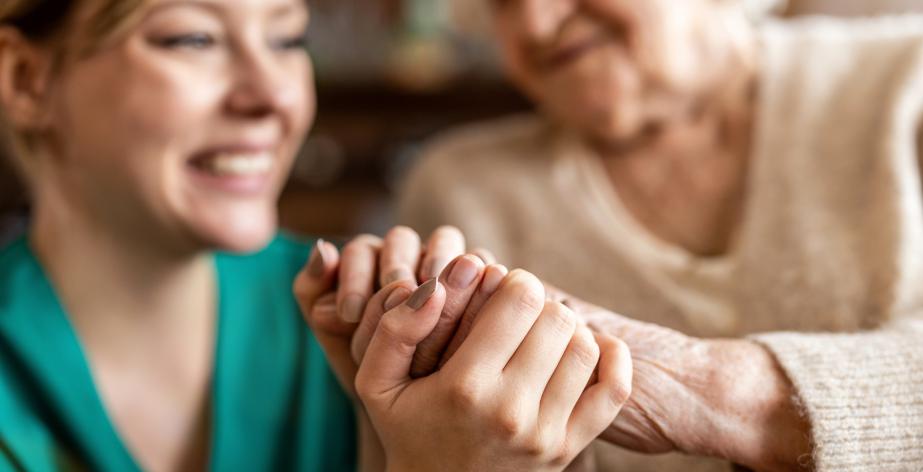 Senior en verzorgster houden elkaar vast