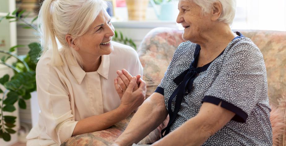 Oudere dame met haar thuishulp, lachend in gesprek