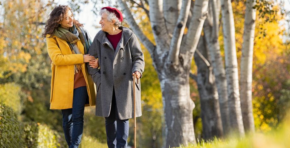 Oudere dame en haar thuishulp wandelen in het bos