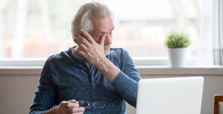 Medewerker zit vermoeid achter de laptop