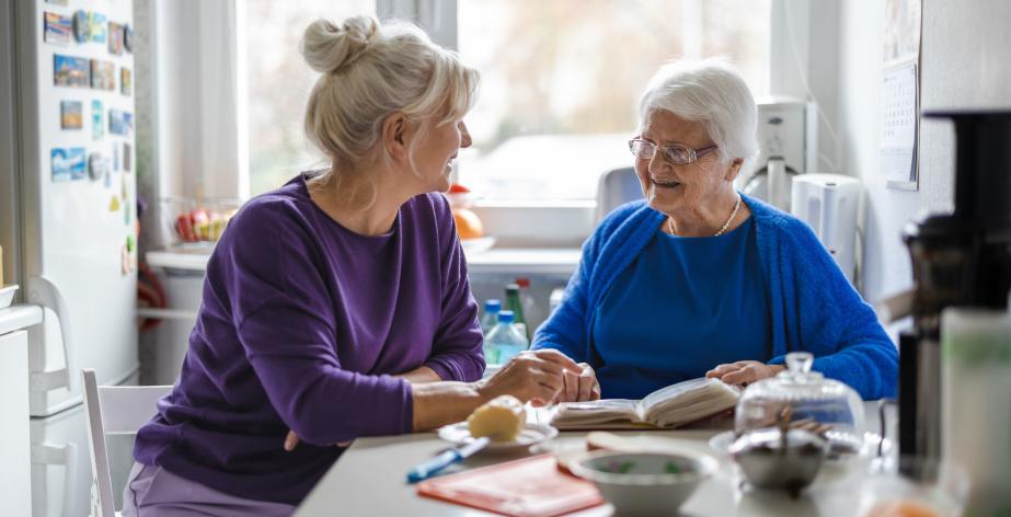 Mantelzorger en senior zitten aan tafel