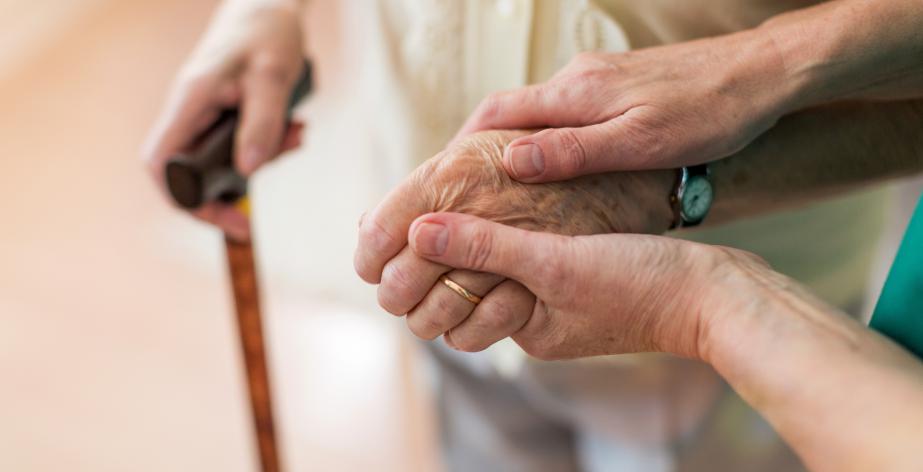 Thuishulp houdt handen van senior vast